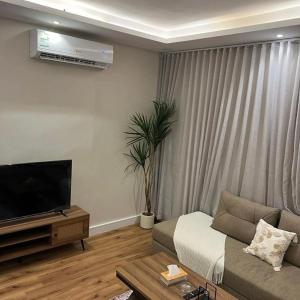 een woonkamer met een bank en een flatscreen-tv bij Smouha in Amman