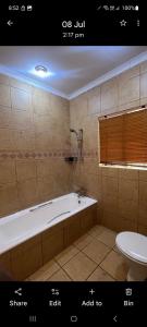 a bathroom with a bath tub and a toilet at Villa La Maison in Pretoria