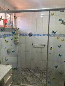ein Bad mit einer Dusche mit Schmetterlingen an der Wand in der Unterkunft Casa no cumbuco in Caucaia + 12 Fotos
