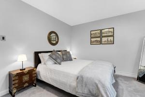 Cozy Bungalow - 5mins to The Ottawa Hospital في أوتاوا: غرفة نوم بيضاء مع سرير وساعة على الحائط