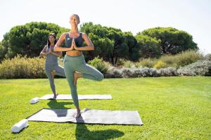 two women doing yoga in a grass field at EPIC SANA Algarve Hotel in Albufeira