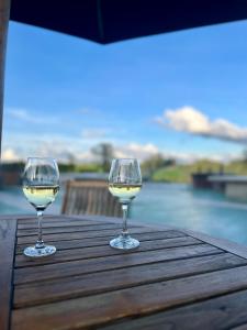 two glasses of white wine sitting on a wooden table at Suites - Llanogrande in Rionegro