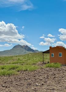 a building in a field with mountains in the background at Cabin at the Hill, Close to Big Bend National Park and Terlingua Ghost Town in Terlingua