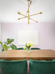 een eettafel met groene stoelen en een vaas met bloemen bij Charming 3 Beds Ossington Home in Toronto