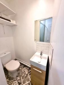 a white bathroom with a toilet and a sink at Studio avec terrasse in Elbeuf +18 photos