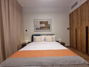 アブダビにあるElegant Pool-View 1BR Near Cleveland Clinicのオレンジとグレーの毛布が掛けられた大きなベッドのある寝室 +29枚の写真