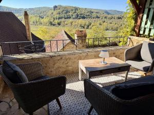 a patio with chairs and a table with a view at Le Coin Tranquille in La Roque-Gageac