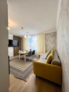 a living room with a yellow couch and a table at Современный 3х комнатный апартаменты на Туране возле Барыс Арена in Astana