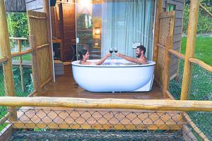 two men sitting in a bath tub on a porch at Tahaa Pousada Boutique in Ilhabela