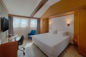 a hotel room with a bed and a desk and a tv at NH Ravenna in Ravenna