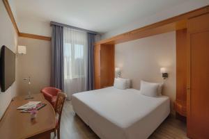 Una habitación de hotel con una cama grande y un escritorio. en NH Ravenna, en Rávena