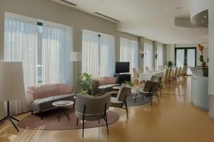 a lobby with a waiting room with tables and chairs at NH Ravenna in Ravenna