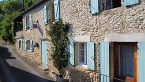 Un edificio de piedra con puertas azules y flores. en Le Coin Tranquille, en La Roque-Gageac