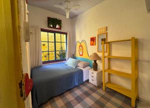 a bedroom with a blue bed and a window at Tia Chica Camburi in Camburi