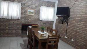 a living room with a table and a television and a brick wall at Cabañas Acacias in San Antonio de Arredondo