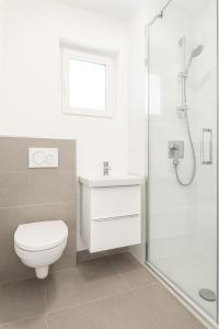 a white bathroom with a toilet and a shower at Lake Lodge Ossiacher See in Annenheim