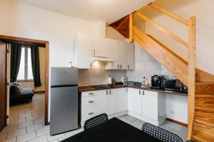une cuisine avec des placards blancs et un escalier dans l'établissement Maison du Beffroi de Mons centre ville, à Mons