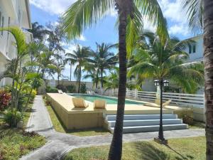 Un patio trasero con un sofá y palmeras y una piscina. en Bella villa, en Flic en Flac 33 fotos más