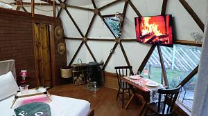 a room with a bed and a table with a fire in it at Domo Cachoeira São Bernardo in Piranguçu