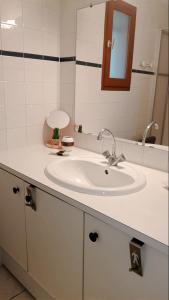 een badkamer met een witte wastafel en een spiegel bij Villa Horizon in Lacanau