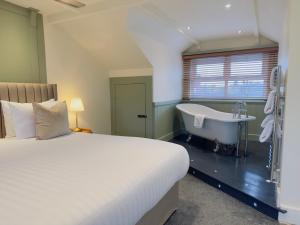 a bedroom with a bed and a bath tub and a sink at The Inn at Cheltenham Parade in Harrogate
