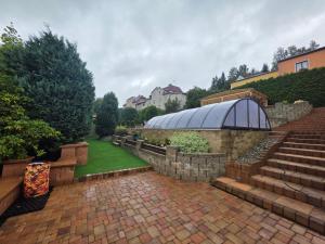 ein Garten mit einer Steinmauer und Treppe und einem Gewächshaus in der Unterkunft Penzion Bedřiška Kraslice in Kraslice