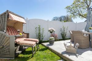 a backyard with a fence and chairs and a table at Schickes Ferienhaus Ostseeperle, 3 Schlafz., 2 Bäder in Zingst