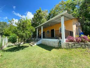 a small yellow house with a stone wall at Casa Cahuí in El Remate
