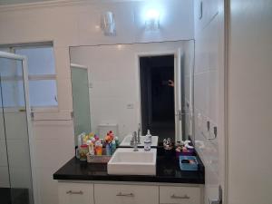 un baño con lavabo y espejo en Quarto em frente a praia do Boqueirão, en Santos