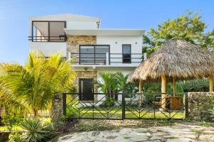 a large white house with a thatch roof at Vista Popoyo 3BR Coastal Retreat with Surf & Mangrove Views in Popoyo