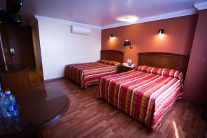 a hotel room with two beds and a table at Gilfer Hotel in Puebla