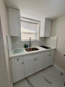 a kitchen with white cabinets and a sink at Guayabita's House in Miami