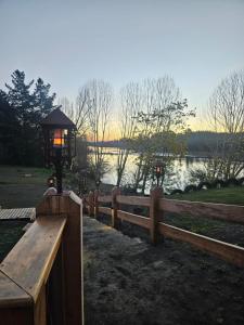 ein Holzzaun mit einer Lampe darauf neben einem See in der Unterkunft Camping Campeon in Salto del Laja