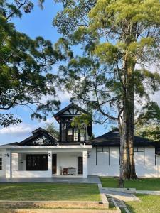 a white house with a black roof and a tree at The Petrichor in Tupai