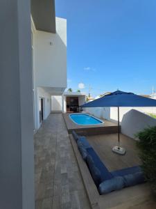 a house with a swimming pool and an umbrella at Refúgio da Praia Aracaju in Aracaju