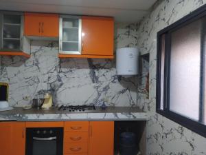a kitchen with orange cabinets and marble walls at appartement en résidence - Bouskoura, Maroc  +7 photos