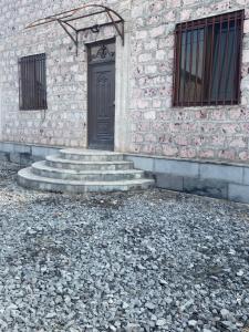 a stone building with a black door and stairs at Уютный дом не далеко от аэропорта in Pʼarakʼar