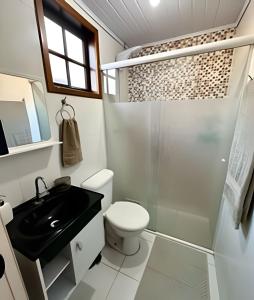 Un baño con inodoro, lavabo y ducha. en Chalé Encanto, Lazer e Piscinas, en Vinicola Girardi