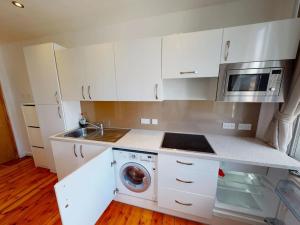 een keuken met witte kasten en een wasmachine bij Heart of Notts, Modern Studio, Great City Views in Nottingham +15 foto's