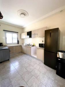 a kitchen with a black refrigerator and a tile floor at Appartement Yoff Oasis in Dakar