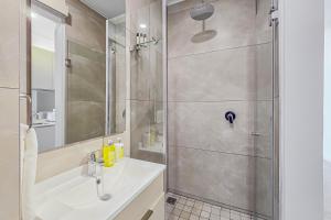 La salle de bains est pourvue d'une douche et d'un lavabo blanc. dans l'établissement One Rosebank CozyCorner, à Johannesbourg