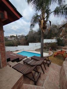 Una piscina con una mesa de picnic y una palmera. en Chalet " La Maruca ", en Villa Carlos Paz