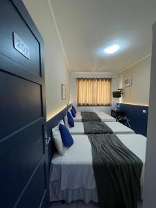 ein Zimmer mit drei Betten mit blauen Kissen in der Unterkunft Copacabana Blue Hotel in Rio de Janeiro