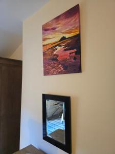 a mirror on a wall with a painting above it at Honeymoon Suite in Llanidloes