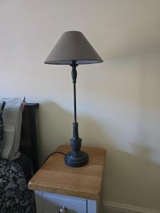 une lampe noire posée sur une table à côté d'un lit dans l'établissement Cozy Double Room - The Unicorn Hotel, à Llanidloes