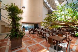 Un restaurante con mesas, sillas y plantas en macetas. en Sunset Palace Beach Hotel - All Inclusive, en Mazatlán