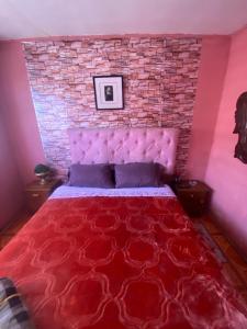 a bedroom with a red bed with a brick wall at Hotel del valle in Melipilla