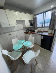 a kitchen with white chairs and a table with green plates at Hostal Quintamar Viña del mar in Viña del Mar