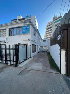 a white building with a gate and a fence at Hostal Quintamar Viña del mar in Viña del Mar