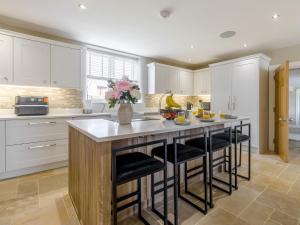 a kitchen with white cabinets and a island with bar stools at 7 Bed in Whitchurch 95835 in Prees